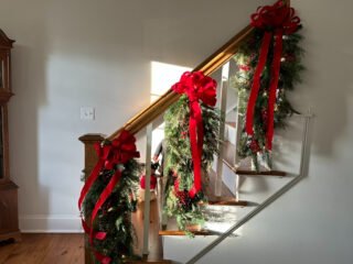 A home staircase is decorated with garland for Christmas