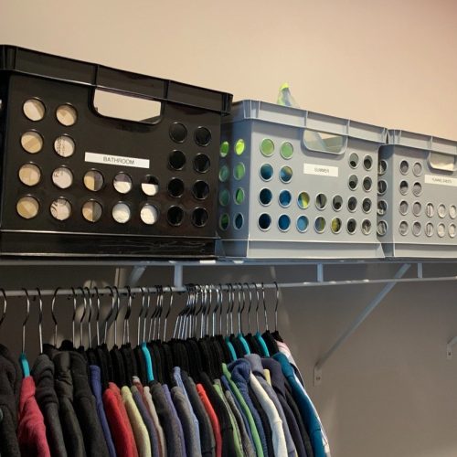 A tidy closet has bins on a shelf for specific items - an orgnized life, ma