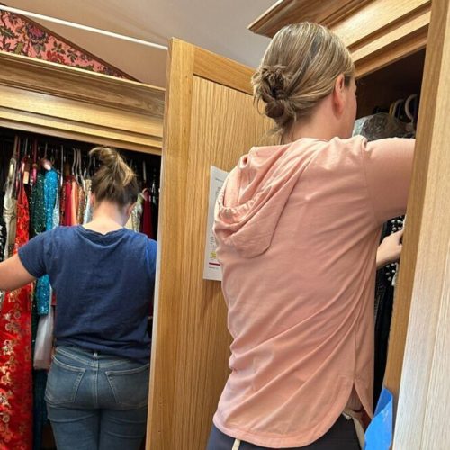 Two professional organizers are organizing a walk-in closet.